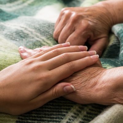 Young Woman's Hand Touching and Holding an Old Woman's Hand